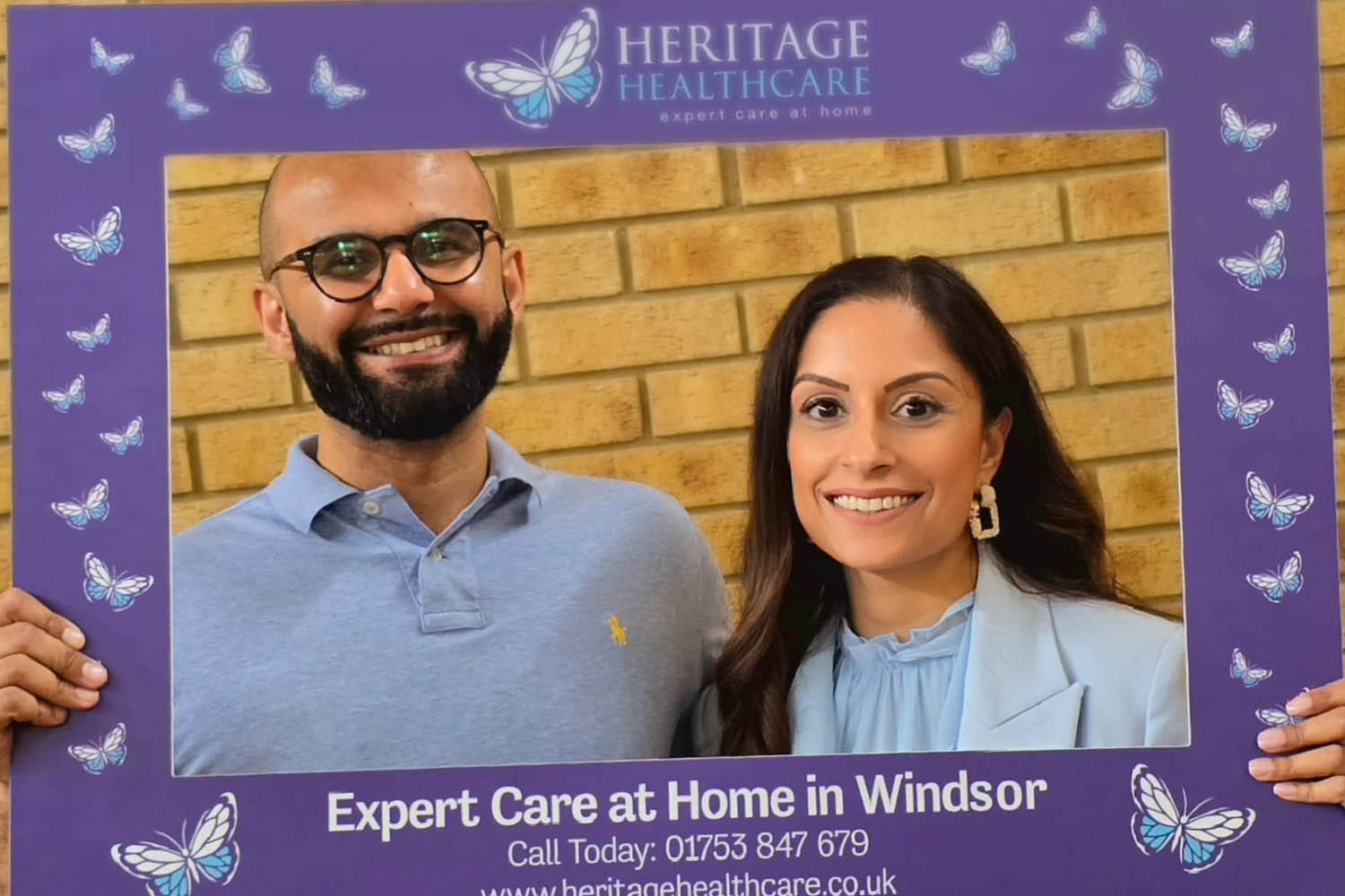 Managing Directors, Prabjot and Tony stood behind the Heritage Healthcare selfie frame smiling at the camera.