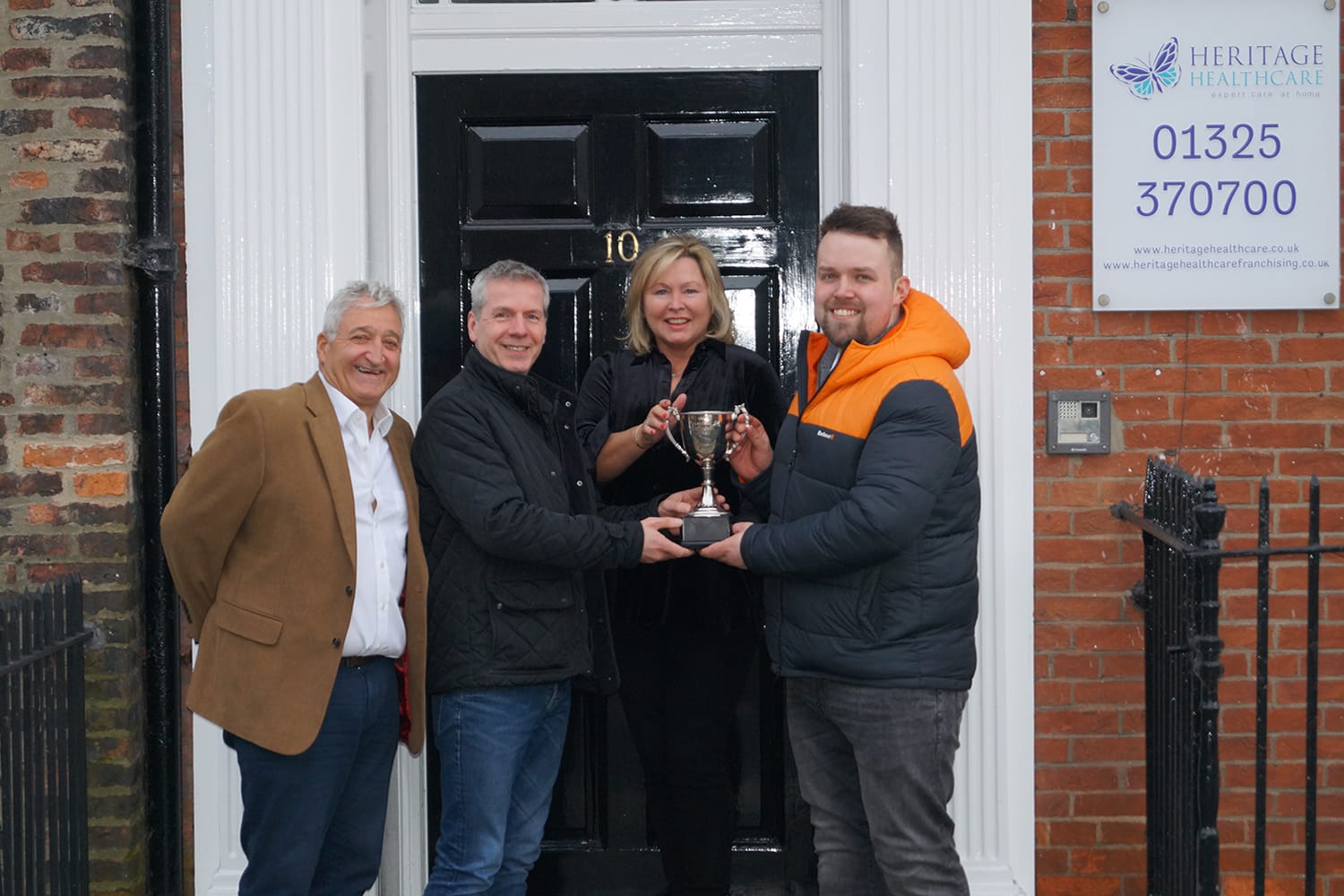 Winners of St Teresa's Charity Golf Day are presented with their Trophy Three male and a female outside of the Heritage Healthcare head office holding a silver golf trophy