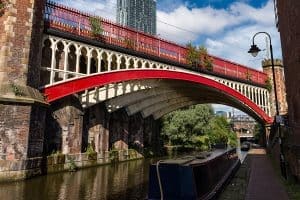 A brightly painted red metal bridge spanning the canal and tow path in Rochdale