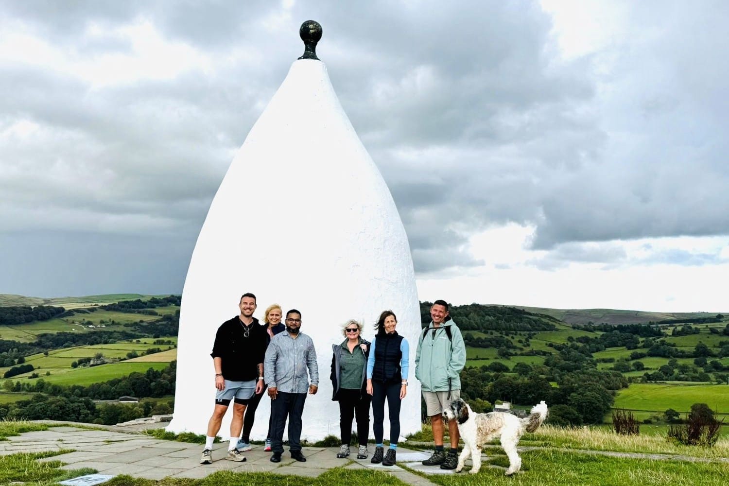Group of walkers in front of a monument at the top of a hill