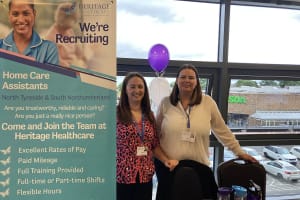 Two ladies, Suzanne and Tanya the owners of Heritage Healthcare North Tyneside & South Northumberland. They are stood next to a tension banner with recruitment information on it.