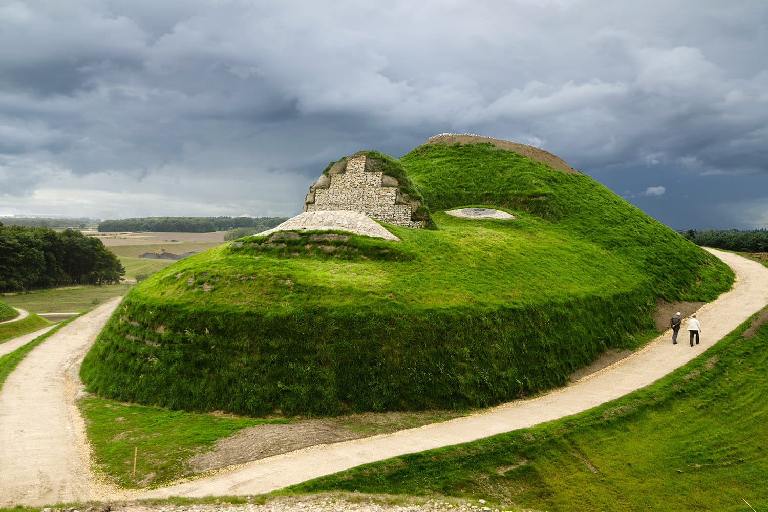 A large grass and stone monument called Northumberlandia or 'The Lady of the North' depicting a face looking up to the sky made from stone on a grass face