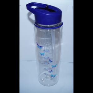 Heritage Healthcare water bottle with time markings, detailing how much water you should have drank by a certain time. The markings start at 8 am and go down to noon before starting at the top from 2 pm till 6 pm. The bottle has a purple top with a purple lid and sipper. The straw inside the cup is see-through.